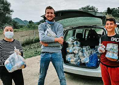 Genti, Eda and Luli standing in front of a car that is full of donated food