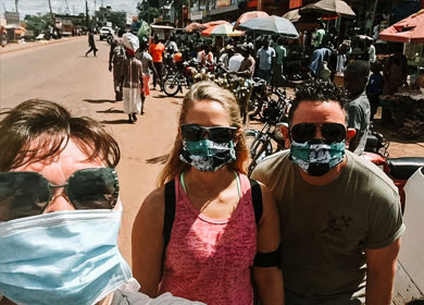 J and D wearing masks and sunglasses on a busy street in Uganda