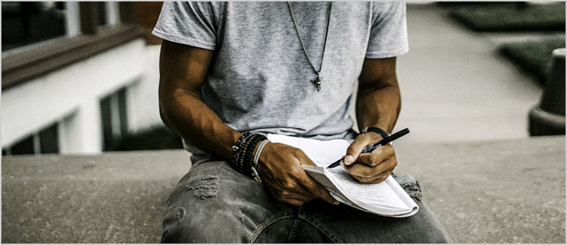Photo of a young man handwriting a note
