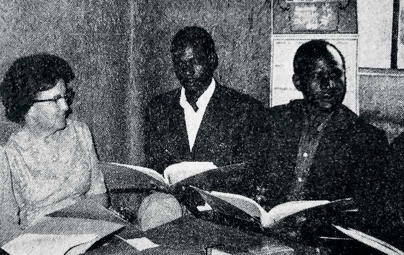 A photo of Lillie Mae Ammerman with two students in a classroom.