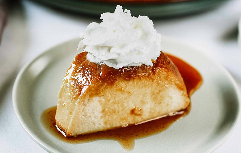 A photo of a slice of Paraguayan Bread Pudding with whipped cream on top