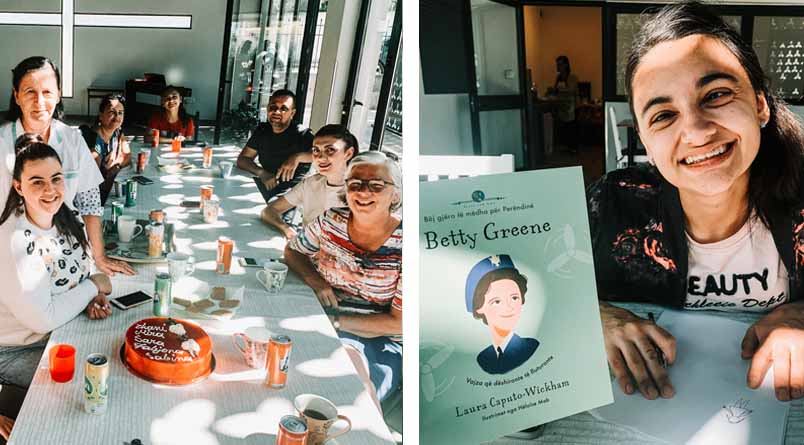 A photo of a group of smiling VT students and adult workers gathered around a long table with a cake, coffee, and soft drinks and a photo of a student with her book.