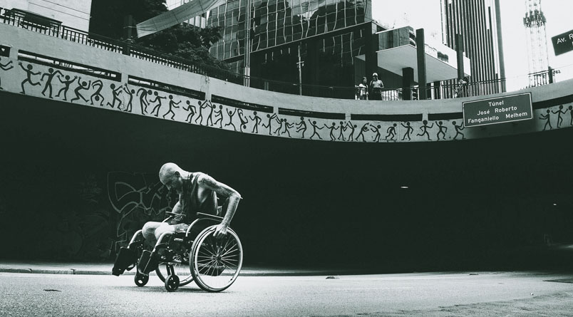A weary athlete in a wheelchair pushing forward.
