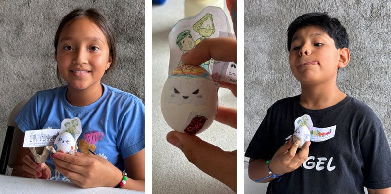 A young girl and boy holding their eggs decorate to look like a person and a hand holding a third egg decorated to look like a person.