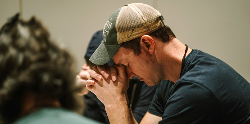 A young man, along with two others, praying.