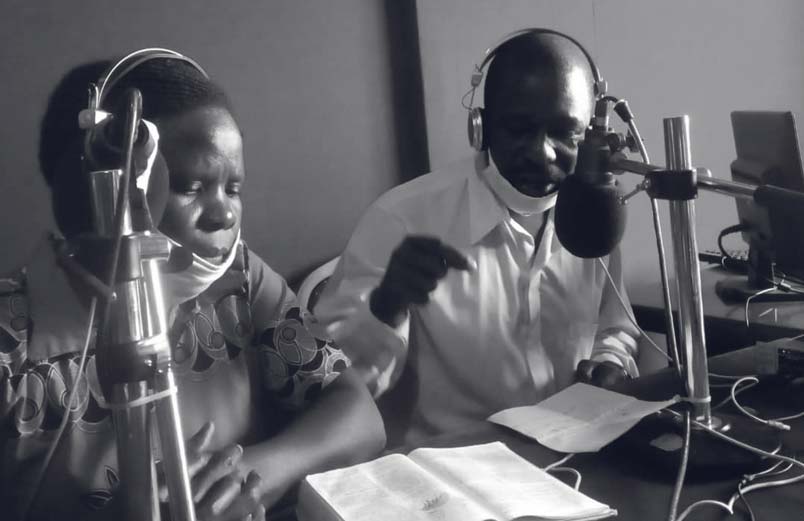 A husband and wife reading from the Bible on a radio broadcast