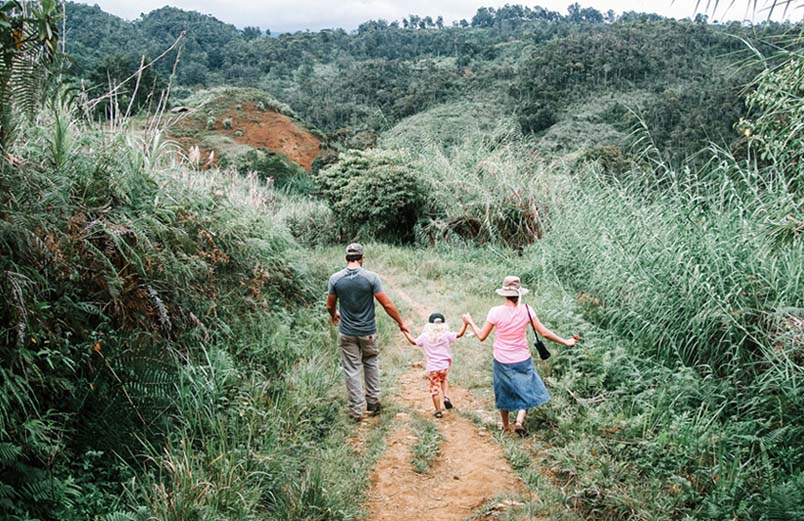 A man, woman, and small child walking down a mountain dirt path